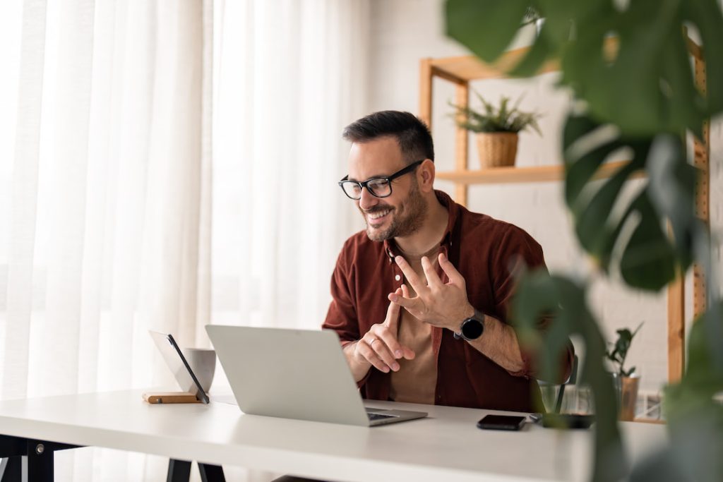 Employee working on a laptop in a hybrid workplace surrounded by office plants