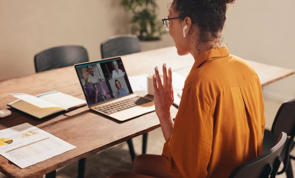 Woman at her desk conversing with a global team over video call