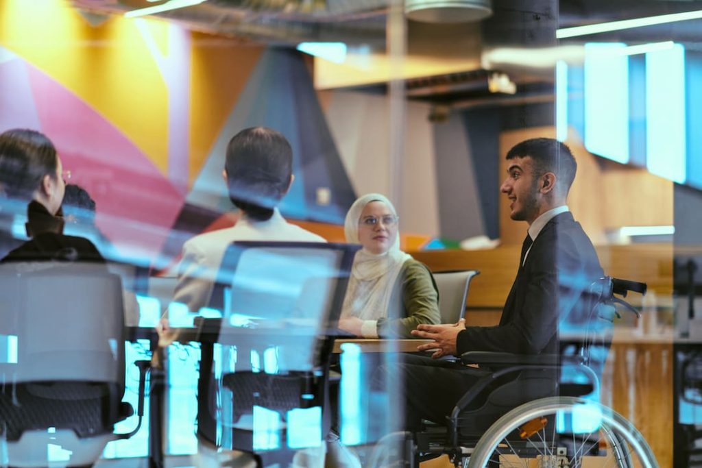 Business director in a wheelchair leading a meeting with a diverse group of employees in an office