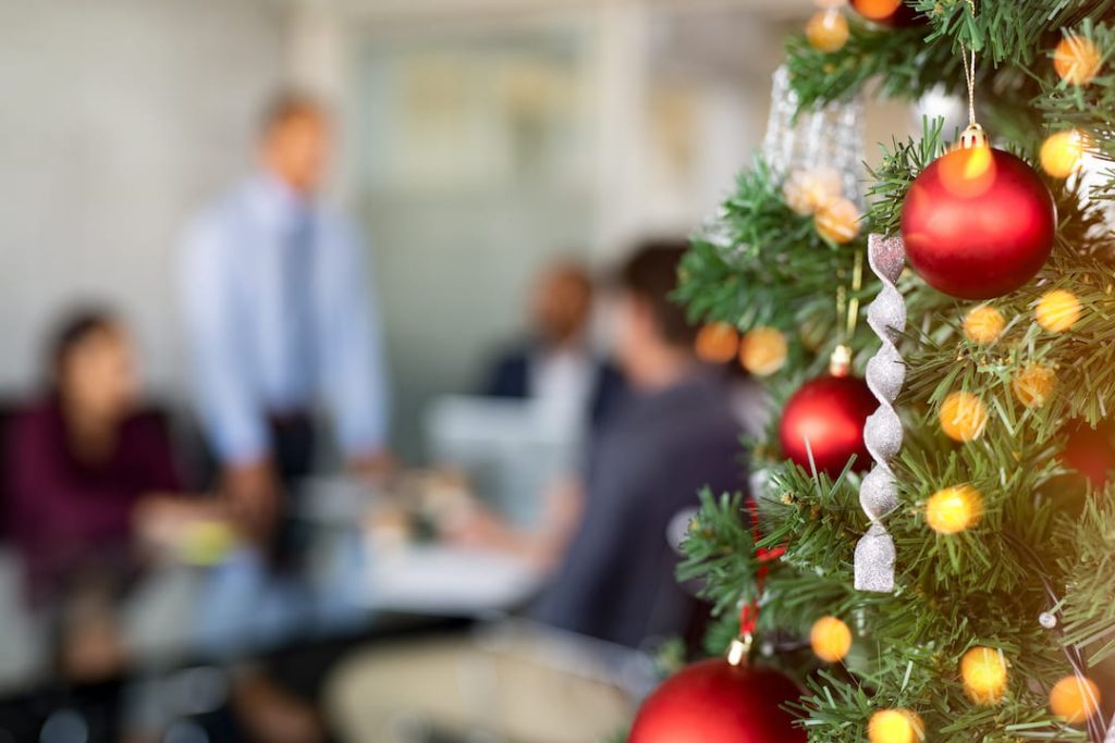 Festive holiday tree in the foreground with blurred office workings working in the background