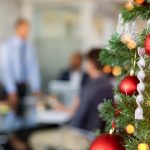 Festive holiday tree in the foreground with blurred office workings working in the background