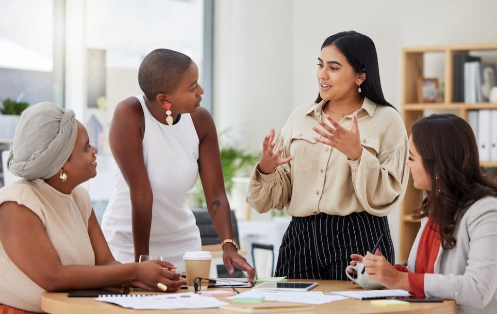 Four employees in an office building having a brainstorming session around a table