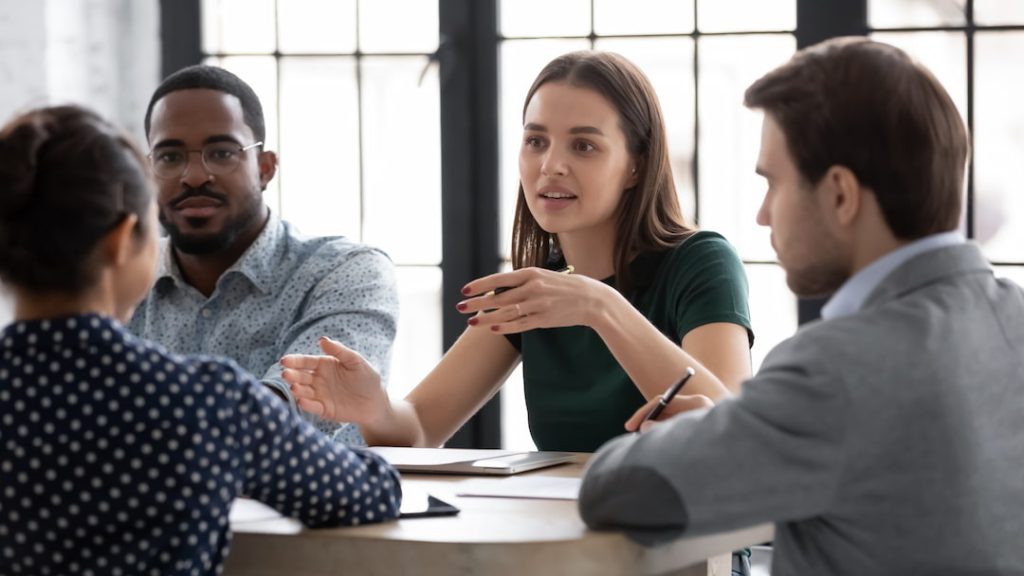 A diverse team learning together by conversing around a table in an office