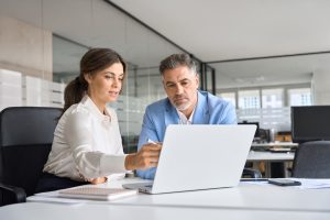 A manager and an employee looking at performance data on a computer during a performance review.